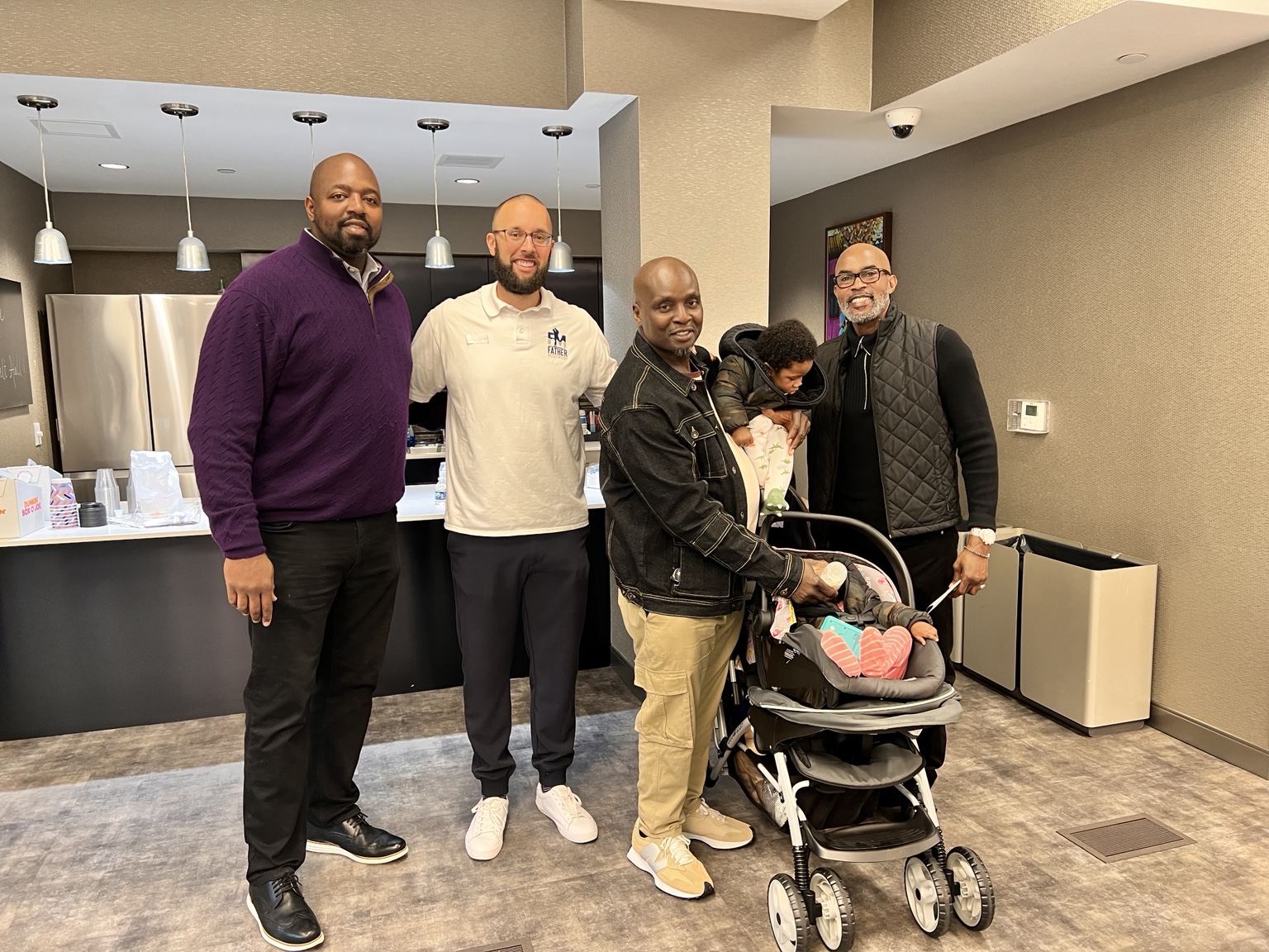 Dr. Grant standing with fellow leaders and a family at a community program gathering
